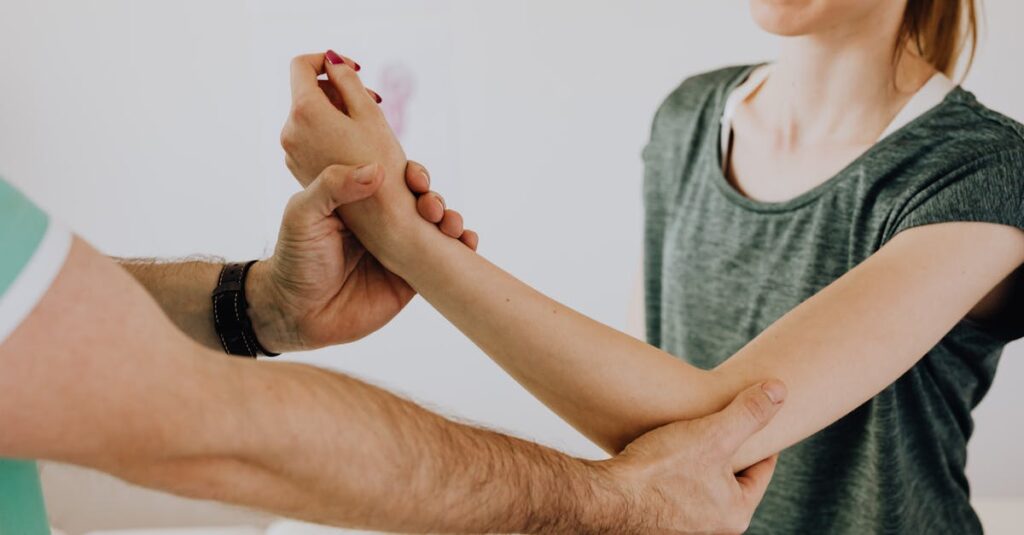 Crop unrecognizable chiropractor examining arm of smiling female patient